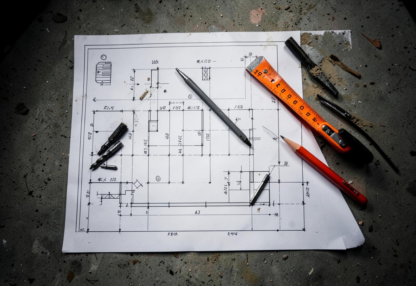 Construction plans, tape measure and diamond core bits on a concrete surface